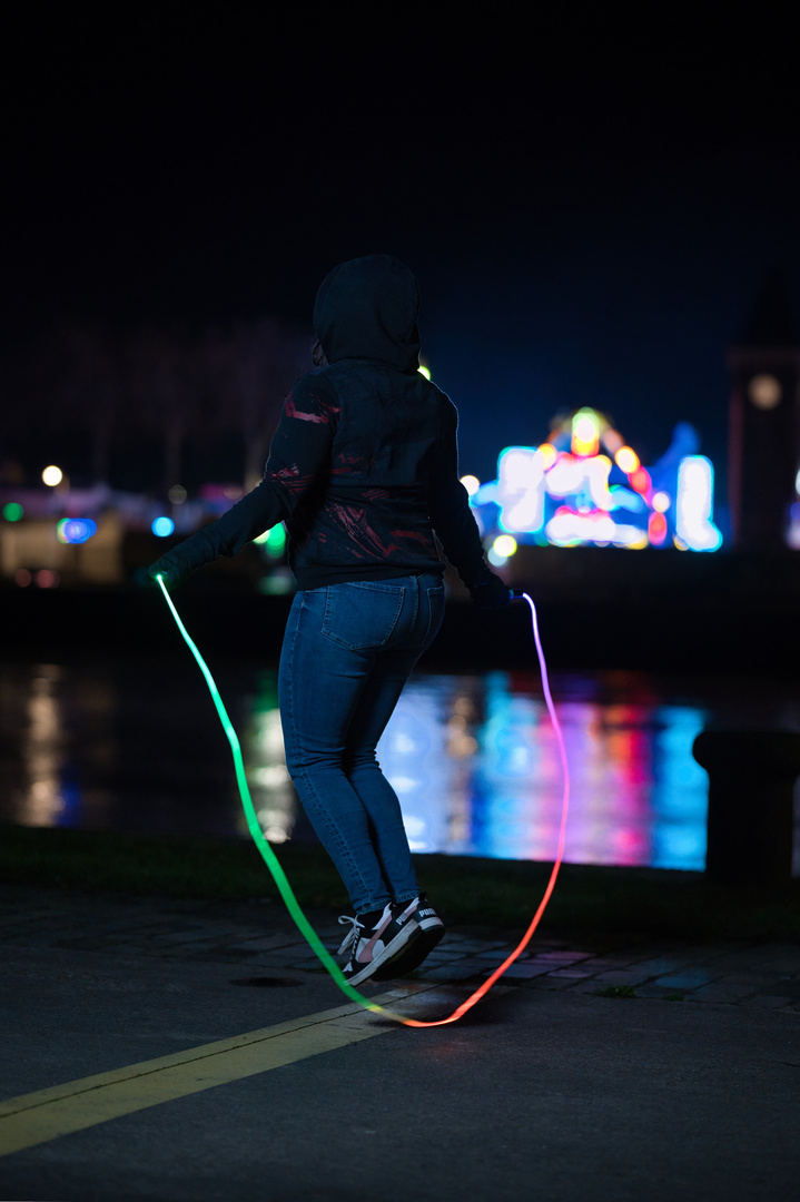 Saut à la corde lumineuse avec des manèges colorés en arrière-plan à Rouen